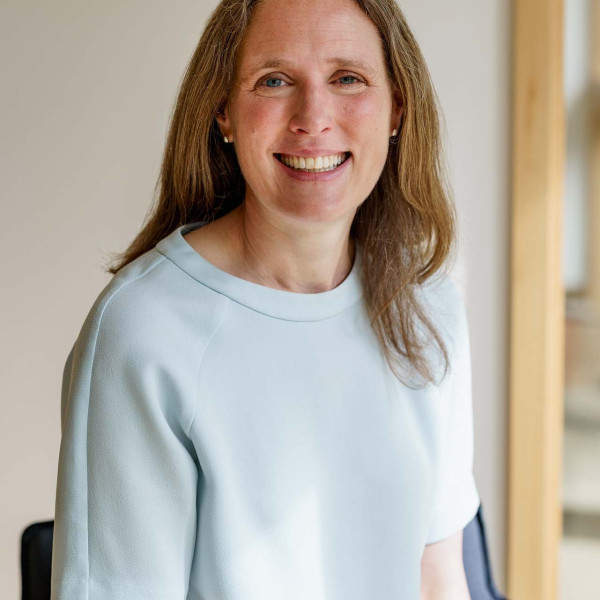 Sarah Davidson, wearing a light blue blouse, sits smiling at the camera.