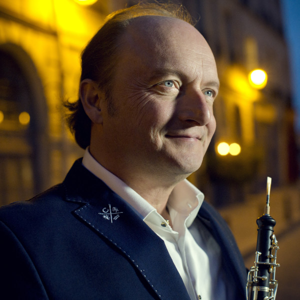 Conductor and oboist François Leleux, seen from the side, holds his oboe, gazing towards the upper right corner of the image.