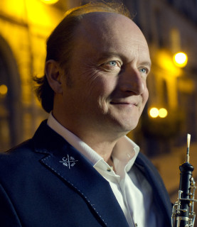 Conductor and oboist François Leleux, seen from the side, holds his oboe, gazing towards the upper right corner of the image.