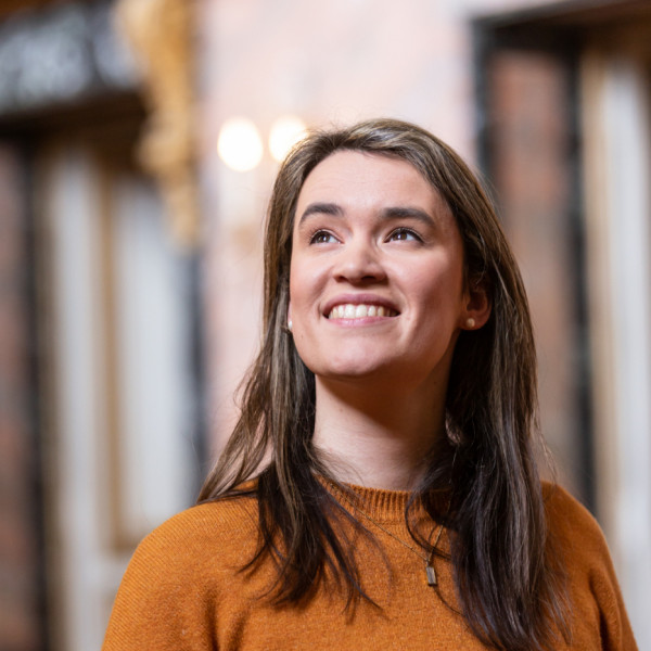 Mezzo-soprano Helen Charlston smiles in sunlight, gazing towards the top left corner of the image.