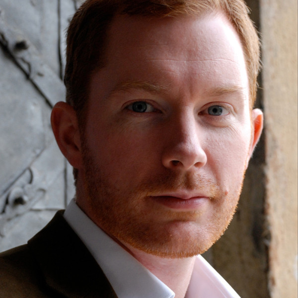 Tenor Robin Tritschler looks directly at the camera with a serious expression.