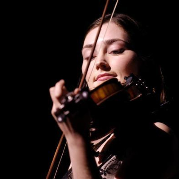 Zoë Conway plays the fiddle with a black backdrop.