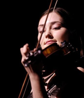 Zoë Conway plays the fiddle with a black backdrop.