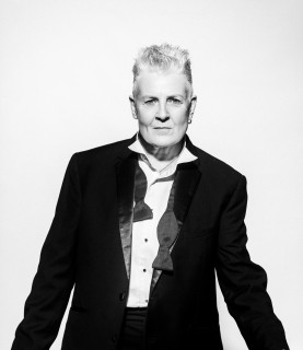 Horse wears a black suit and bowtie untied.