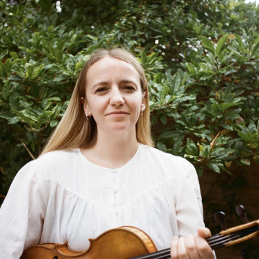 Hatty has long blonde hair and holds her violin