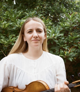 Hatty has long blonde hair and holds her violin