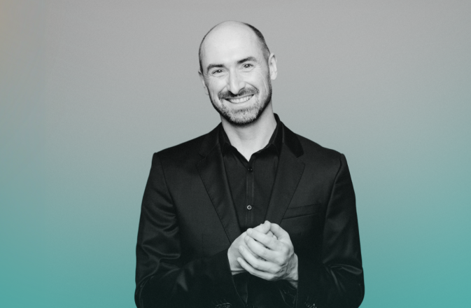 Peter Whelan wears a black shirt and smiles.