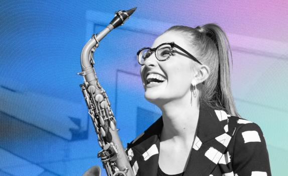Jess Gillam smiles up holding her saxophone.