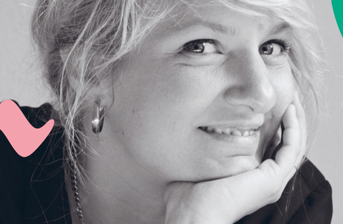 Composer Andrea Tarrodi leaning forward with one arm resting on a surface and her face resting on the palm of her other hand.