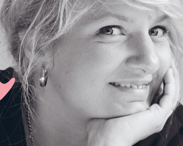 Composer Andrea Tarrodi leaning forward with one arm resting on a surface and her face resting on the palm of her other hand.