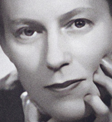 Composer Ruth Gipps leaning forward with both hands gently touching her face.