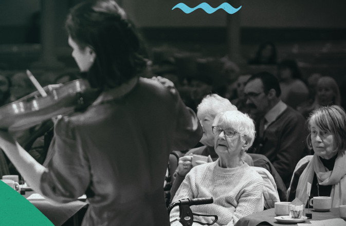 Shot from behind a violinist playing to the audience at a dementia-friendly concert.