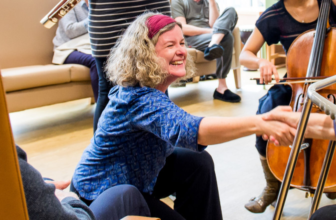 Jane bentley reached and shakes a hand with an older man. The image is cropped on Jane smiling.