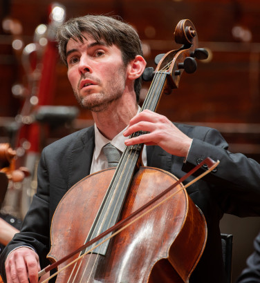 A man plays the cello, his bow on the string
