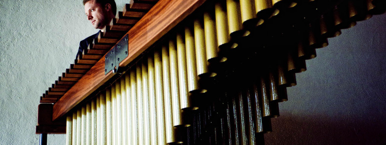 A marimba seen sideways on from a low angle, with Colin Currie just visible behind it