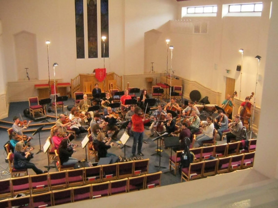 Image shows an Orchestra rehearsing in a hall