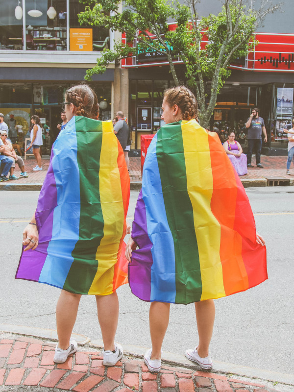 Two girls wearing rainbow cloaks