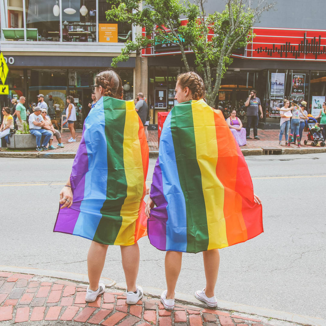 Two girls wearing rainbow cloaks