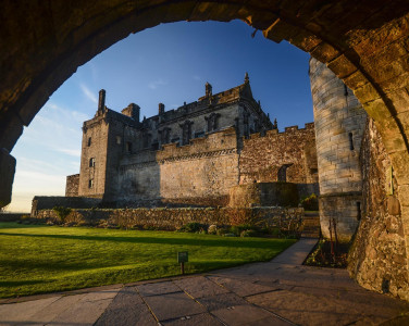 Part of Stirling Castle shot through an arch with Queen Anne's garden in the foreground.