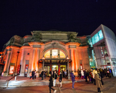 The main entrance of the Usher Hall in Edinburgh in the evening. The building is illuminated by light beams in the dark.