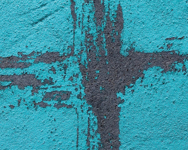 A grafitti holy cross symbol on a blue brick wall