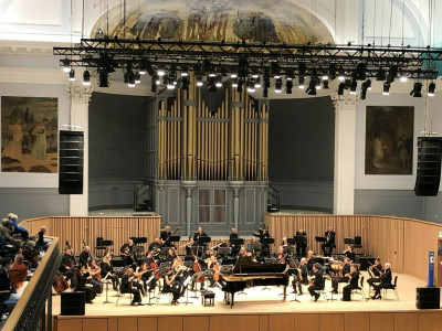 Orchestra sit on stage at the Aberdeen Music Halll, with piano in centre of stage